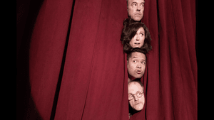 Four actors peer out from a split of a red stage curtain with various expressions of concern