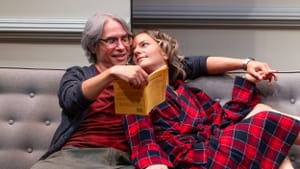 The actors lounge on a couch reading a play together, O’Hare wearing red-checked bathrobe, one hand entwined with Hernandez’s