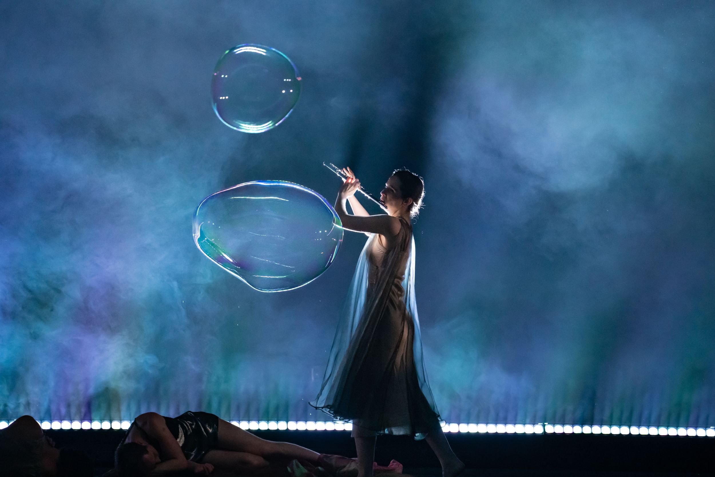 Ferguson, in a flowing transparent shift, plays the flute against a dramatic misty background with two huge soap bubbles.