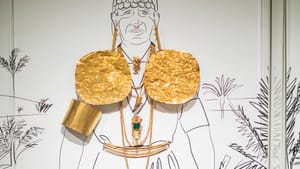 A life-size illustration of a Coclé man sports real-life bright gold plates, jewelry, belt, and armband.