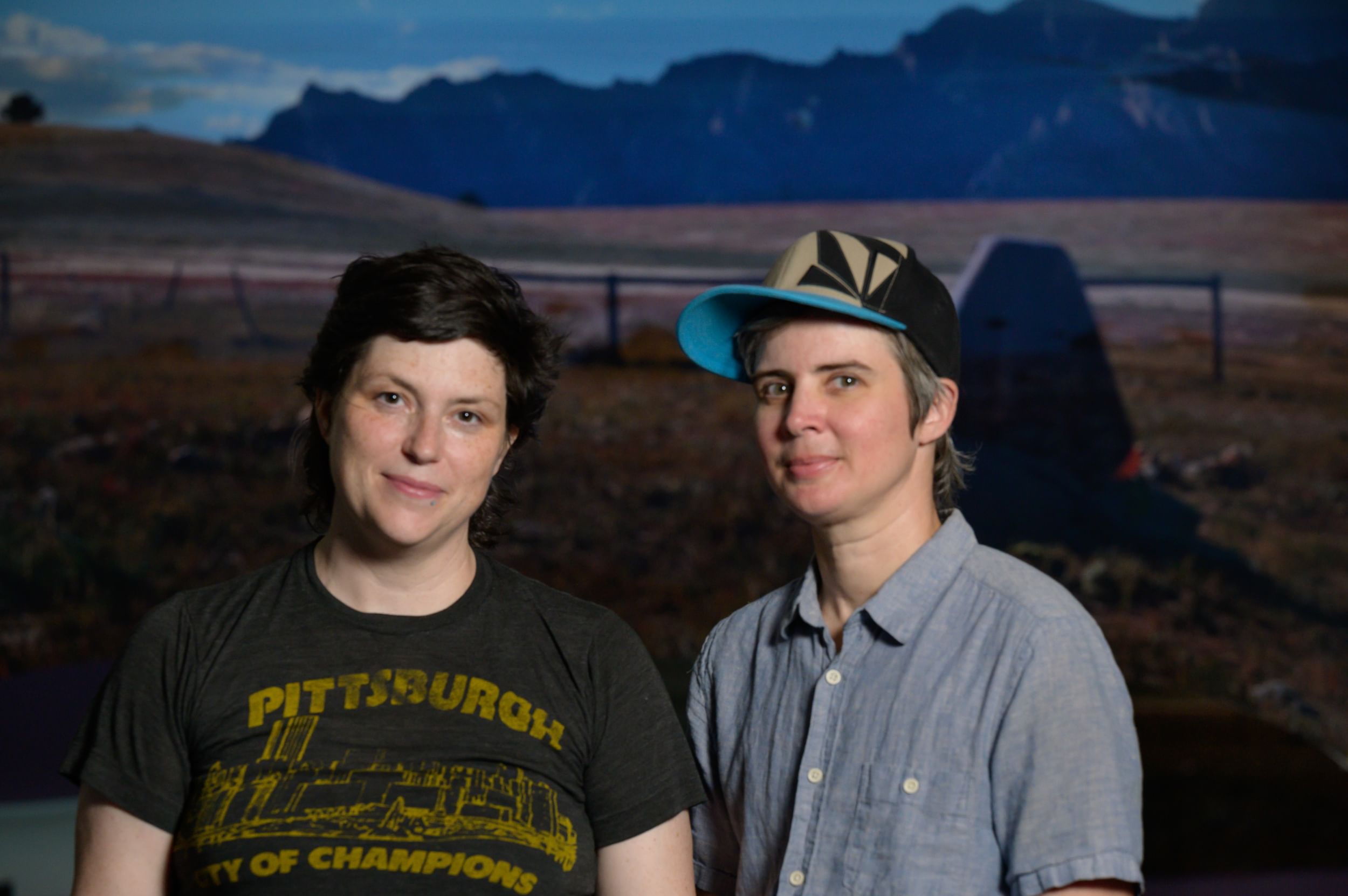 Foley and Jones stand next to each other, long grass field and trees behind them