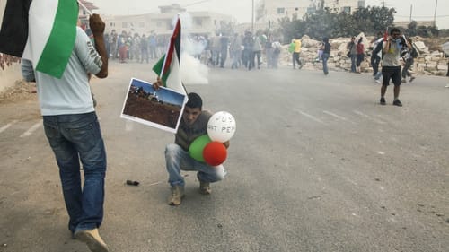 A Palestinian man takes cover from tear-gas canisters at 2010 protest in the West Bank village of Al Ma'asara. (Image courtesy of Slought.)