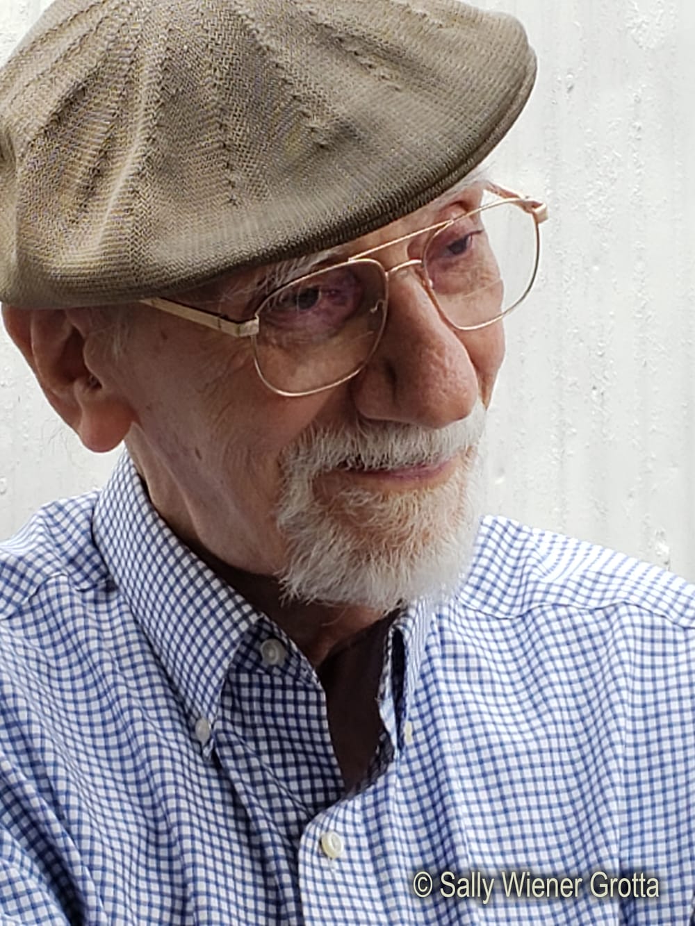 Close-up of Tom, an elderly white man, with glasses, a tan cap, white goatee, and calm smile.