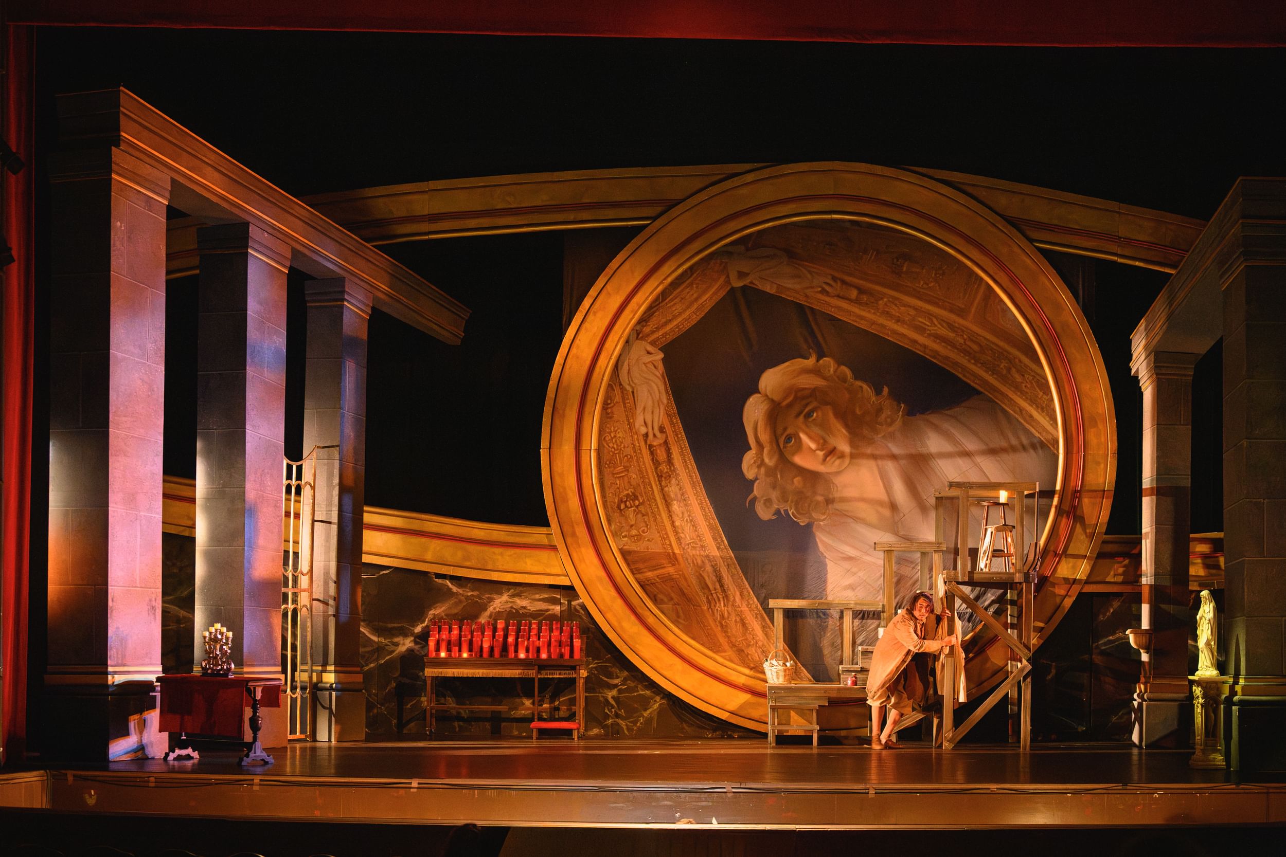 A large, architecturally arresting opera set featuring a circle 20+ feet high framing a giant, tilted painting of a sad woman