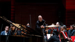 Nézet-Séguin passionately conducts Trifonov on a gleaming grand piano, with orchestra members around them.