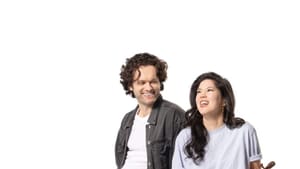 Portrait. Two performers sit on bar stool chairs in all-white room. Wong holds a violin.