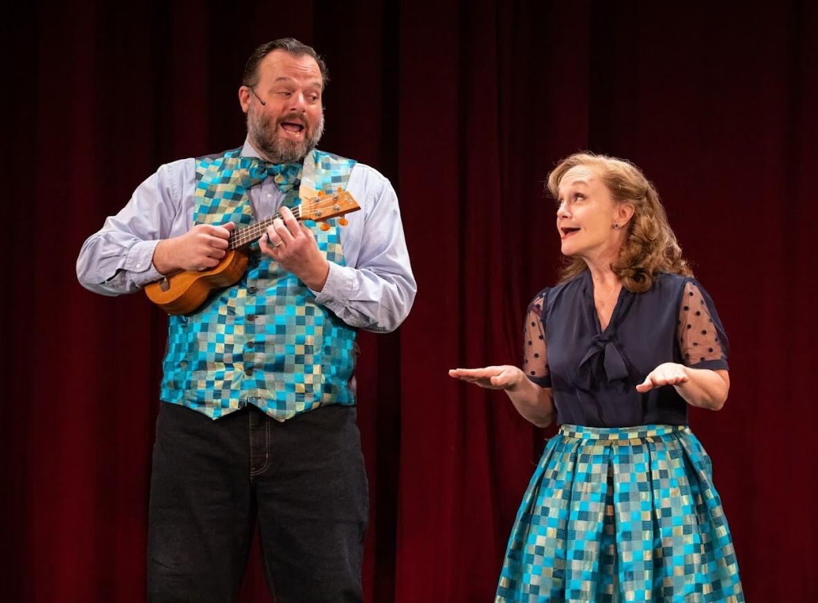 Greer & Childs, in matching gold & blue-checked satin outfits, sing together as Greer plays a ukelele.