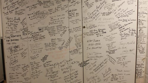 Photo of a white wall inside the ship, covered with hundreds of small handwritten messages and signatures.