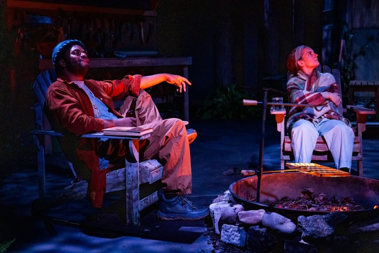 On a set like the outside of a woodland cabin, the actors sit in Adirondack chairs at night, looking contemplatively up.