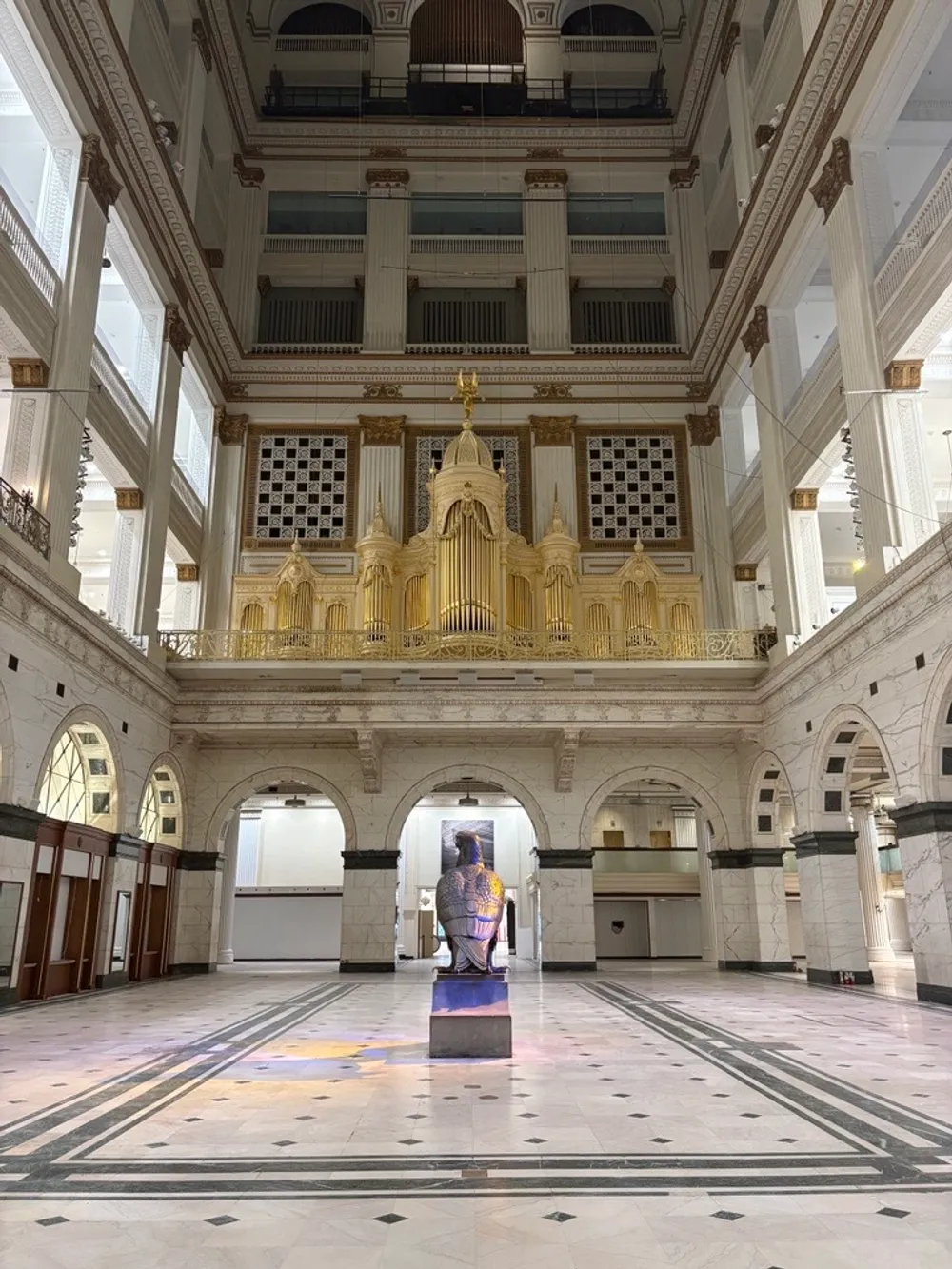 View from ground floor looking up at the grand architecture of the Court, giant gold organ one story above the marble floor