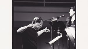 A black and white photo of Krzywicki, in all black, his arms and hands out as he conducts soprano Kidwell in front of him