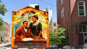 Colorful rendering on the side of the building shows Still seated & writing next to his daughter, wearing a stethoscope