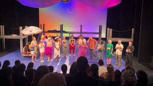 View from the audience of a standing ovation at the Wilma, with the cast and stage manager lined up joyfully under the lights