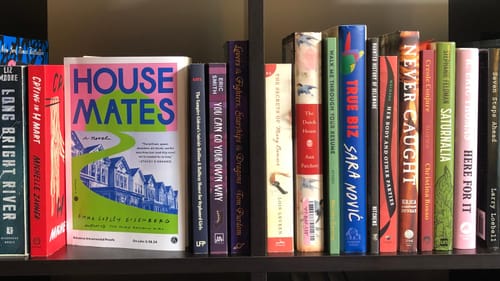 Two bookshelf cubbies holding 22 different books by Philly authors including Emma Eisenberg, Eric Smith & R. Eric Thomas,