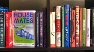 Close-up on two black square bookshelf cubbies crammed with different books by local authors.