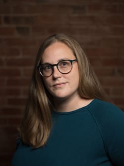 Alaina is a 39-year-old white woman w blond hair and glasses, wearing a turquoise shirt. She has a friendly, alert expression