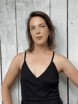 Pam Hetherington is a white woman in her 40s with short brown hair, wearing a black tank top, with her hands on her hips.