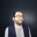 Headshot of Samuel Dunsiger, a white man with a short beard and glasses. He wears a gray shirt with a black vest.