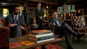 Three men dressed in black suits look towards someone or something off camera, in a densely wood-furnished room.