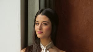 Portrait shot of Dueñas, wearing a white gown and holding a violin.