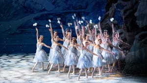 A group of women dancers in (mostly) white dresses pose in uniform on stage.