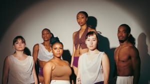 Six dancers in various combinations white and black tops and bottoms pose, a ring of light cast over them